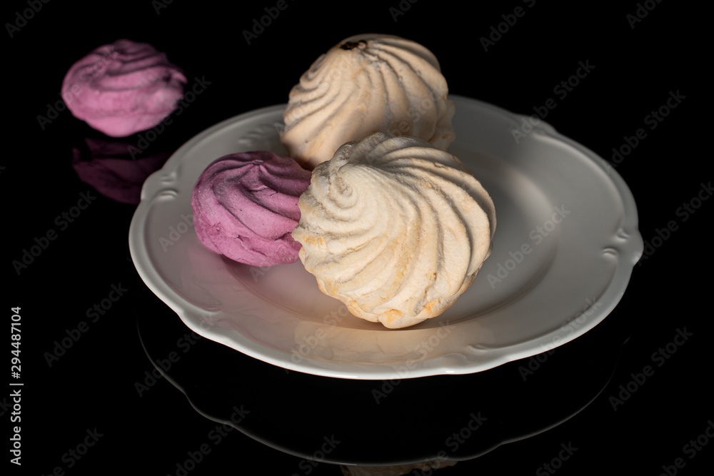 Group of four whole fresh pastel zefir on white plate isolated on black glass Group of four whole fresh pastel zefir on white plate isolated on black glass