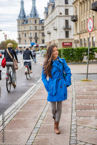 Asian tourist woman walking in Copenhagen city street next to bike path, modern commute. Urban living lifestyle young happy person commuting in fall or spring. © Maridav