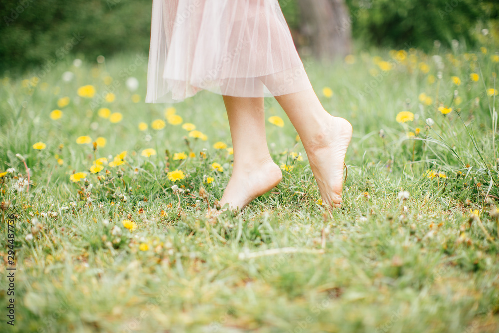 legs of young barefoot women wearing pink dress standing on one leg on  green grass with yellow flowers, close up, summer outdoors фотография Stock  | Adobe Stock