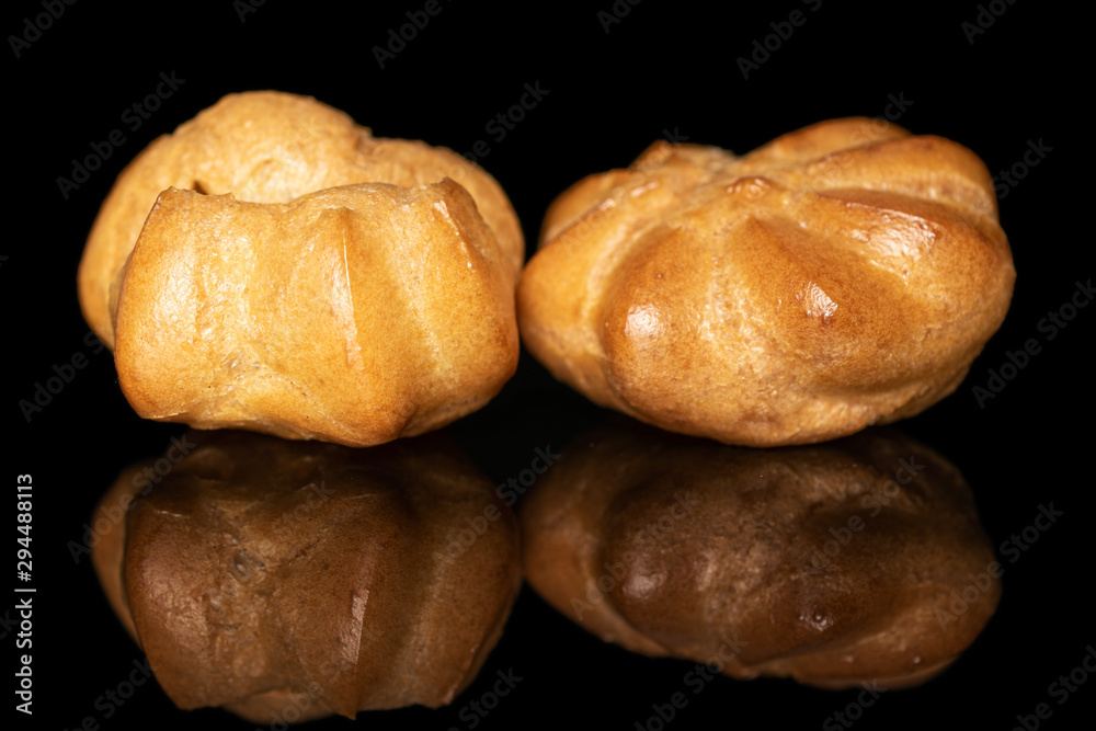 Group of two whole fresh baked golden profiterole isolated on black glass Group of two whole fresh baked golden profiterole isolated on black glass