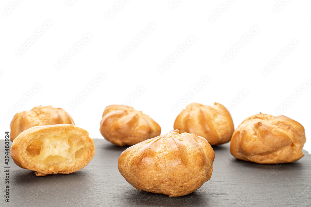 Group of five whole one half of baked golden profiterole on grey stone isolated on white background