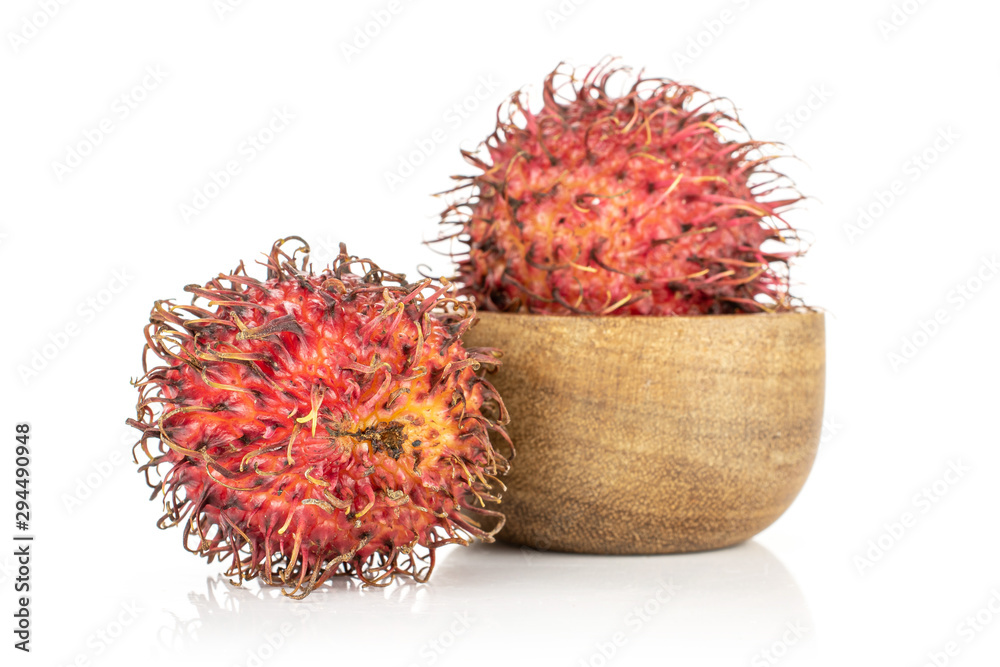 Group of two whole unpeeled fresh red rambutan in wooden bowl isolated on white background Group of two whole unpeeled fresh red rambutan in wooden bowl isolated on white background