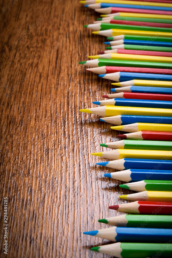 Different colored pencils on the brown wooden table background .Top view .Close up .Color .Pencil.Set Different colored pencils on the brown wooden table background .Top view .Close up .Color .Pencil.Set