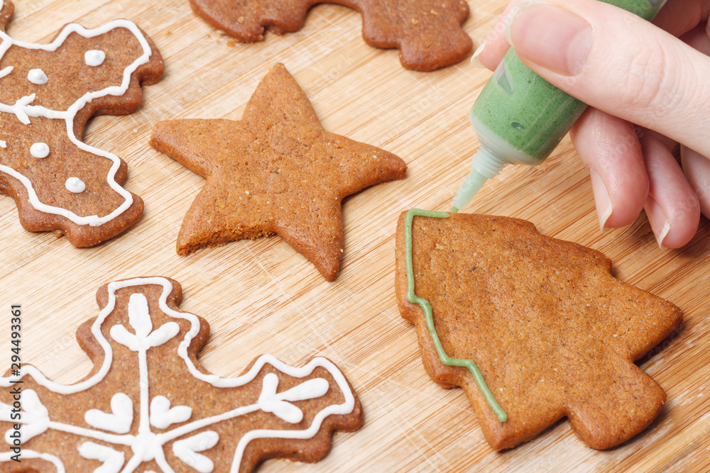 Christmas gingerbread biscuits decorating process with green icing.