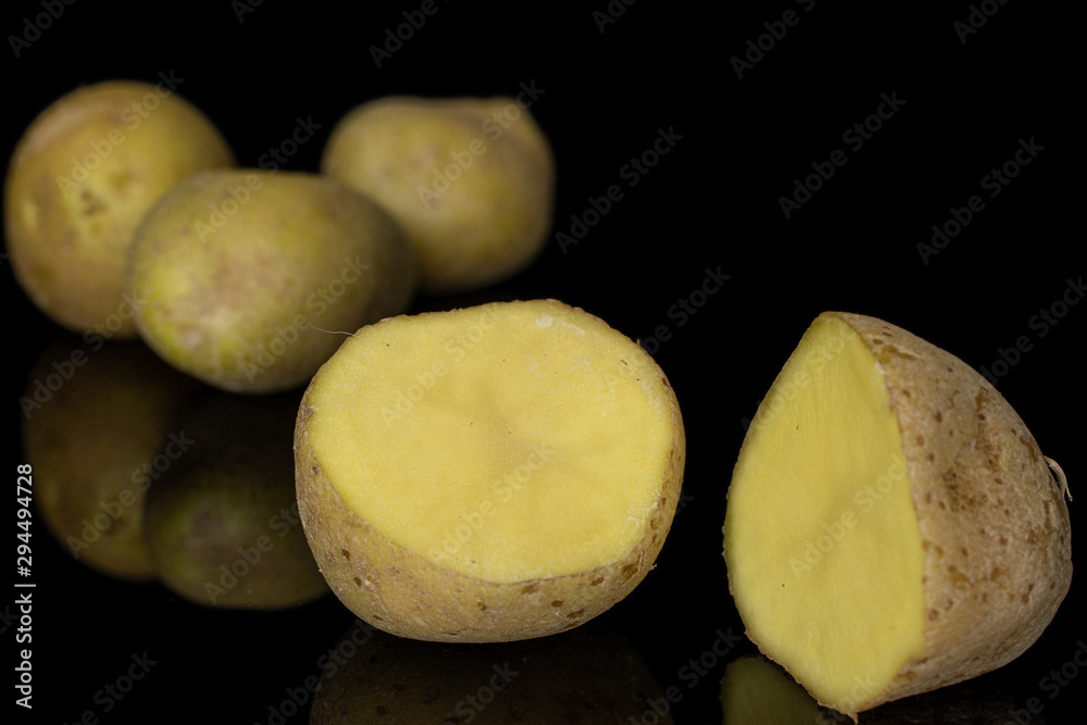 Group of three whole two halves of raw brown potato isolated on black glass