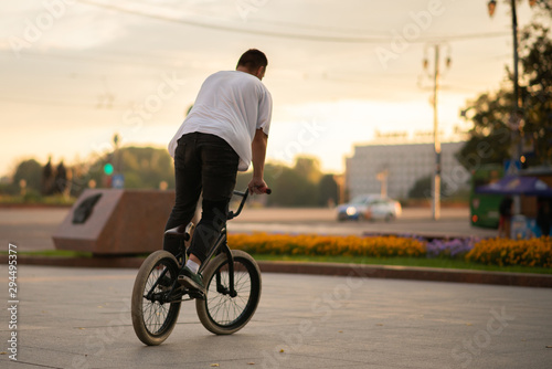 The guy, standing at full height, rides a BMX bike.