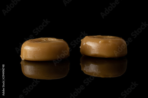 Group of two whole caramel brown candy isolated on black glass photo