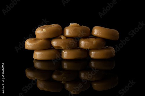 Lot of whole caramel brown candy isolated on black glass photo