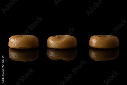 Group of three whole caramel brown candy isolated on black glass photo