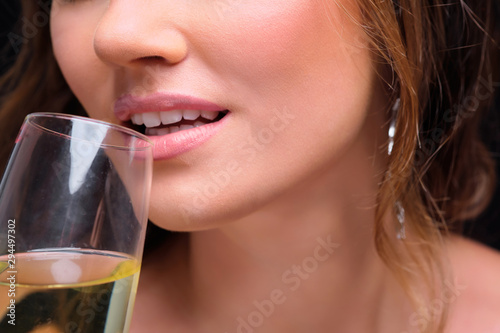 Close-up of young elegant woman drinking champagne against black background.