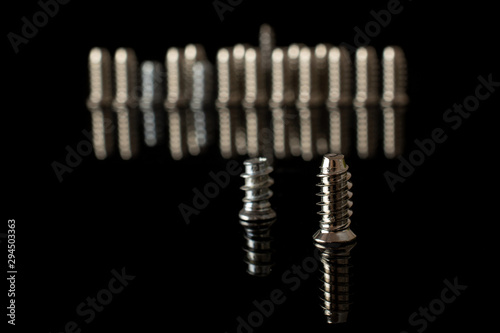 Lot of whole metallic glossy bolt isolated on black glass