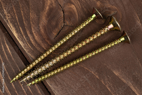 Group of three whole long metallic glossy bolt flatlay on brown wood photo