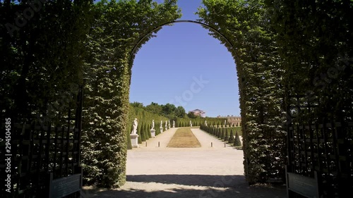 Tracking shot of coming into Versailles gardens with statues going out of alleys with bushes