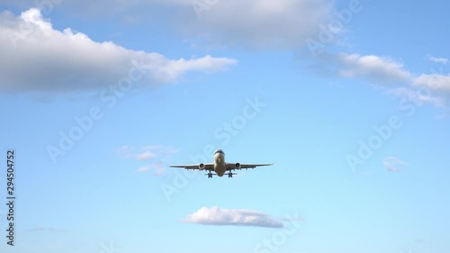 Modern large plane flies in the sky. Beautiful blue sky and white clouds in the background. The aircraft flies overhead. Airplane takes off or landing. Ultra HD footage. 4K