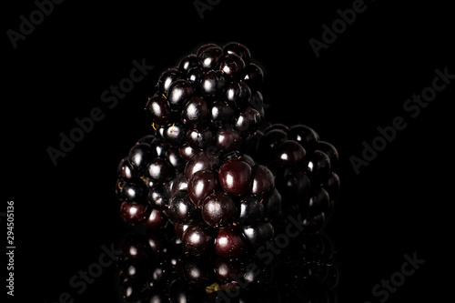 Group of four whole fresh black blackberry isolated on black glass photo