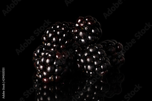 Group of five whole fresh black blackberry isolated on black glass