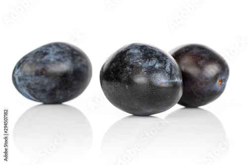 Group of three whole fresh purple plum front focus isolated on white background
