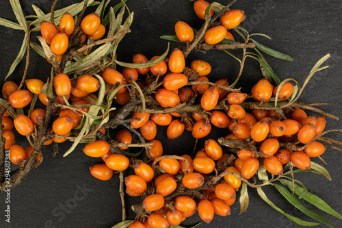 Lot of whole ripe orange sea buckthorn berry flatlay on grey stone photo