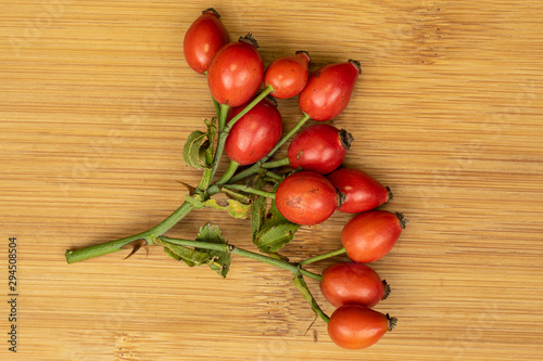Lot of whole fresh red rosehip flatlay on light wood