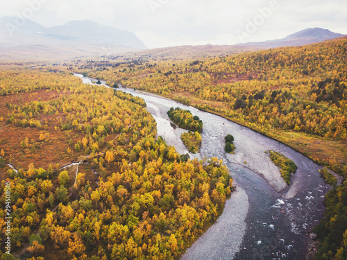 Aerial sunny fall autumn view of Abisko National Park  Kiruna Municipality  Lapland  Norrbotten County  Sweden  shot from drone  with Abiskojokk river  road and Nuolja mountain