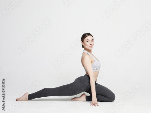 Young woman practicing yoga, working out, wearing sportswear, studio shoot over white background