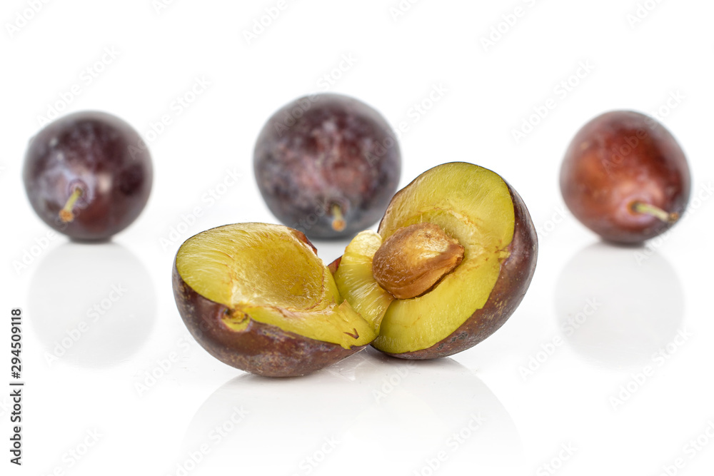 Fototapeta premium Group of three whole two halves of sweet purple plum isolated on white background