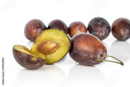 Group of seven whole two halves of sweet purple plum isolated on white background