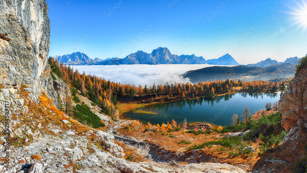 Stunning aerial view of  crystal clear Lake Federa in Dolomites Alps under sunlight in mist and fog