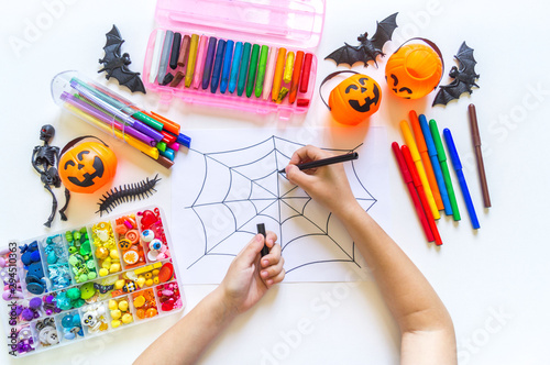 Child draws a rainbow cobweb. Drawing halloween Crayons