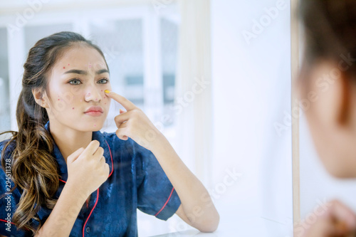 Fototapeta Naklejka Na Ścianę i Meble -  Beautiful teenage girl touching pimples on her face