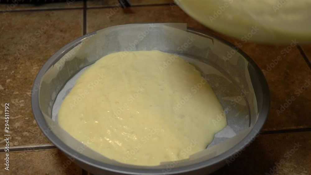 Close up, Pouring vanilla cake batter into round pan Close up, Pouring vanilla cake batter into round pan