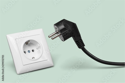 White electrical plug in the electric socket on a wall photo