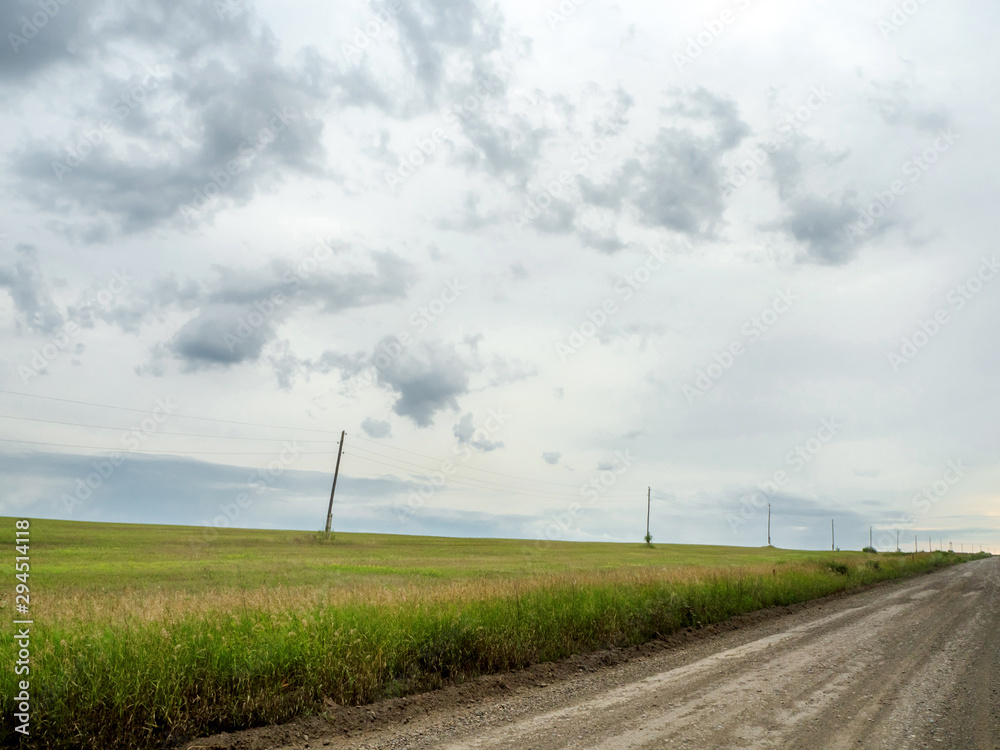 autumn rainy landscape. The road along the field outside the city with a power line