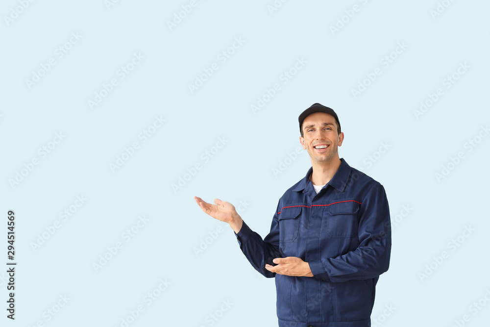 Male car mechanic showing something on color background Male car mechanic showing something on color background