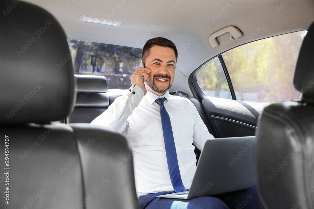 Successful businessman talking by phone in modern car