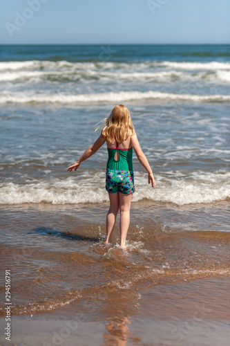 Young blonde girl paddling in the sea on a sunny day