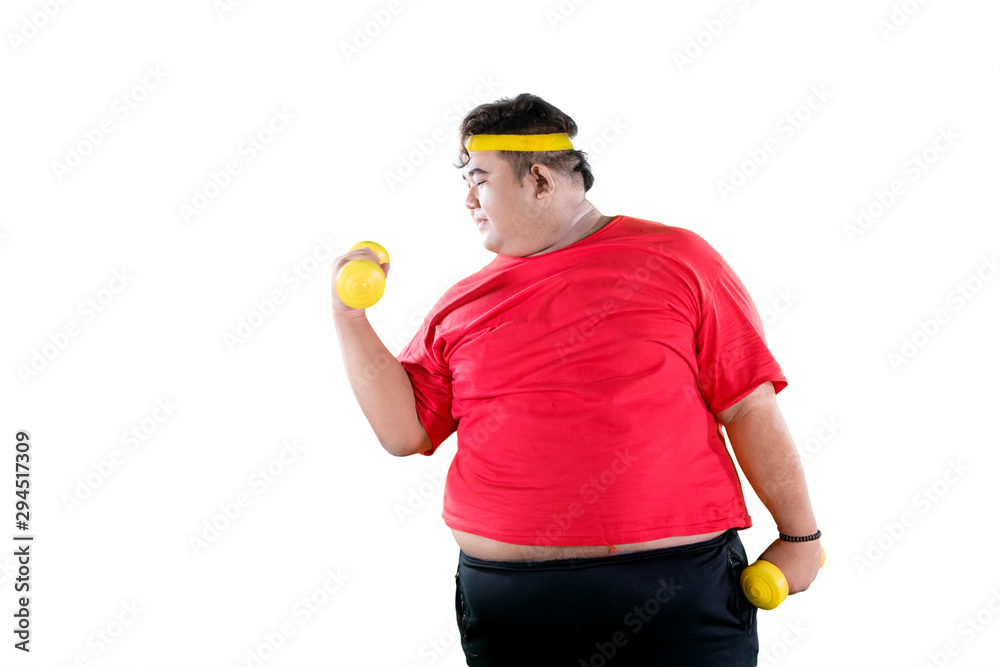 Young obese man exercise with dumbbells on studio Young obese man exercise with dumbbells on studio