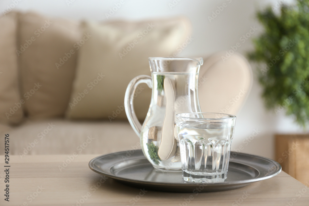 Glass and jug of fresh water on table in room Glass and jug of fresh water on table in room