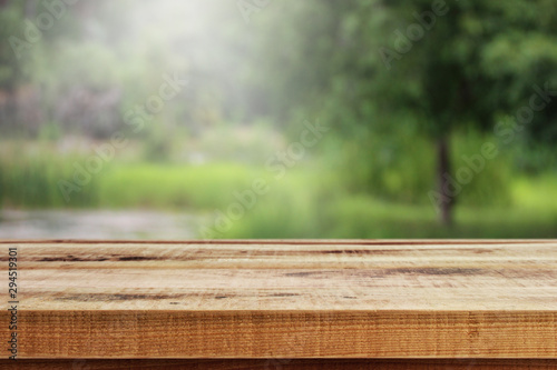 Blurred abstract green bokeh of garden and wooden table background.