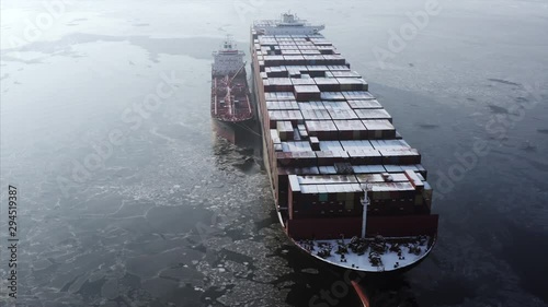 Aerial zooming out view of big cargo ship with contaners in icy Eastern Bosphorus strait. Foggy winter morning. Vladivostok, Russia photo