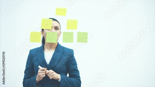A businessman write on glue notes on a glass wall in the workplace. Adhesive note paper reminder calendar to discuss creative idea. Business brainstorming.