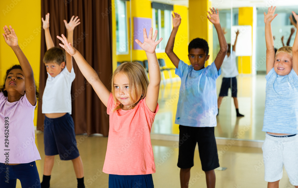 Fototapeta premium Portrait of smiling children practicing sport dance in modern dance hall