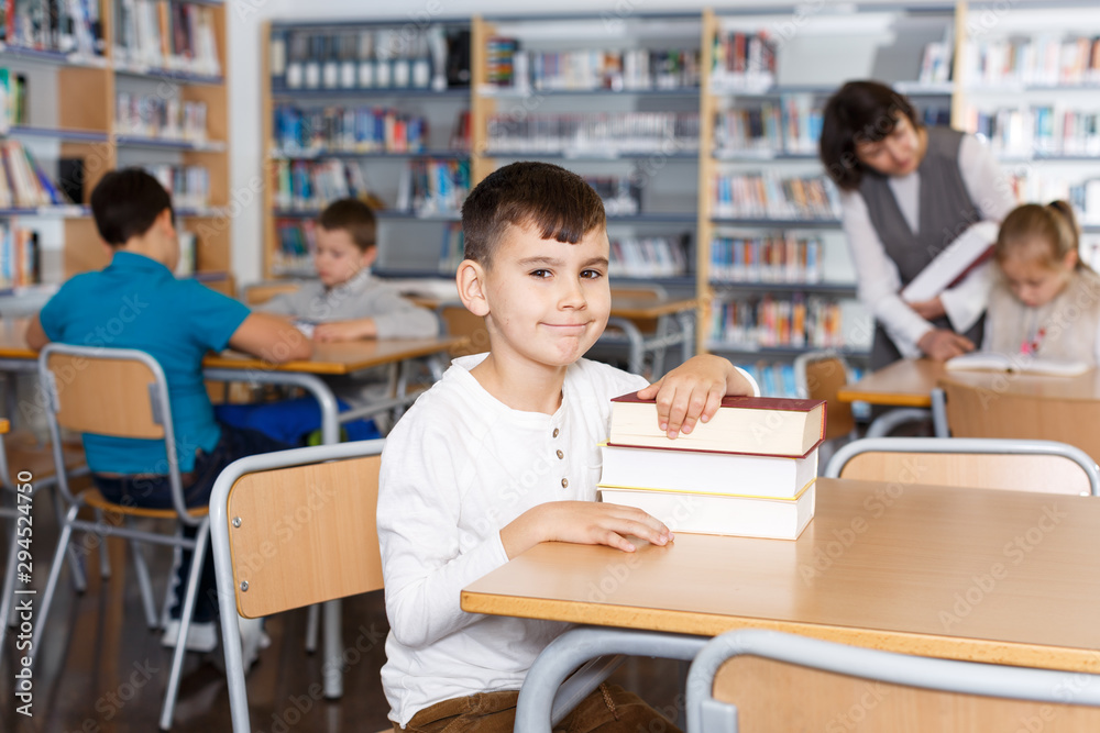 Smiling boy sitting with pile of books