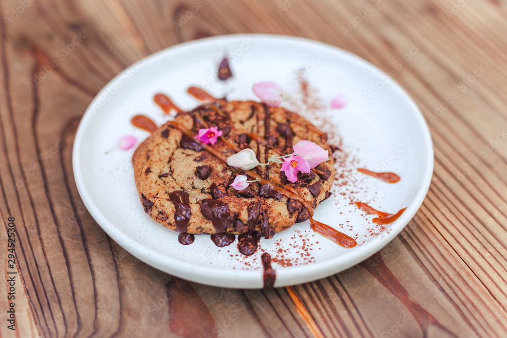 chocolate cookie with caramel on cerabic dish with flower on wooden table chocolate cookie with caramel on cerabic dish with flower on wooden table