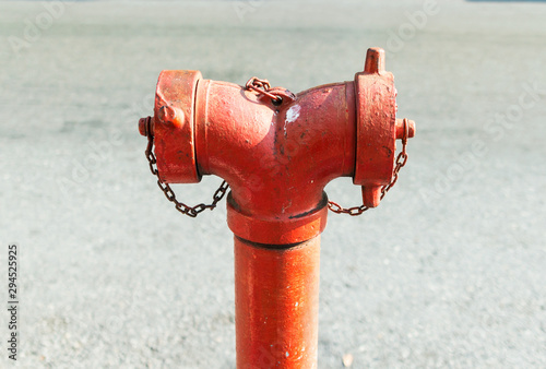 Close up red standpipe hydrant system for fire prevention and fighting standing on footpath with blurred street background.
