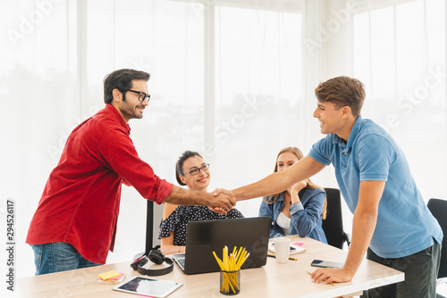 Marketing team. Group of young modern people in smart casual wear discussing something while working in the creative office.