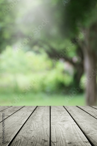 Blurred abstract green bokeh of garden and wooden table background.