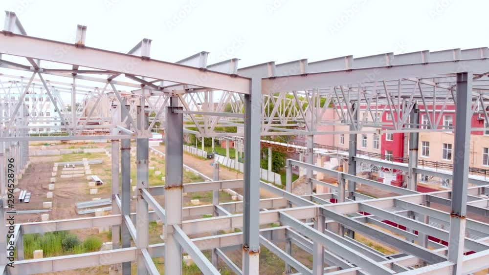 Aerial flight rise above the metal frames of the building under construction. Metal piles streak in the shot. Taken by drone Aerial flight rise above the metal frames of the building under construction. Metal piles streak in the shot. Taken by drone