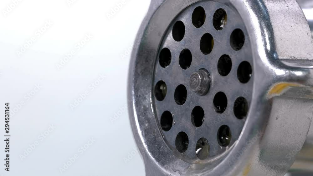 Orange is scrolled through a meat grinder and it comes out in small pieces through holes and juice, too, close-up Orange is scrolled through a meat grinder and it comes out in small pieces through holes and juice, too, close-up
