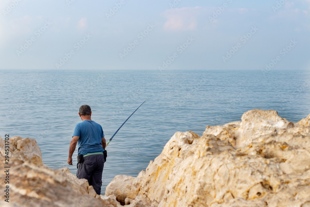 fisherman with fishing rod on the seashore.